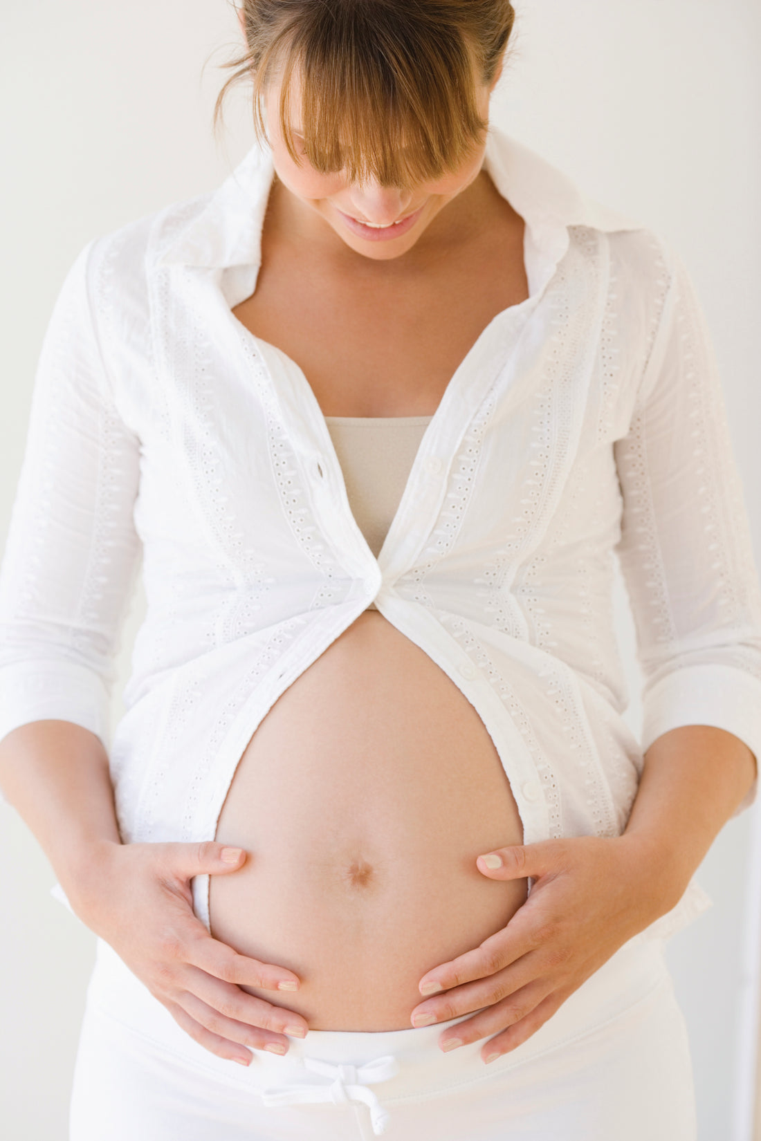 Pregnant woman with exposed belly | Nourish Baby