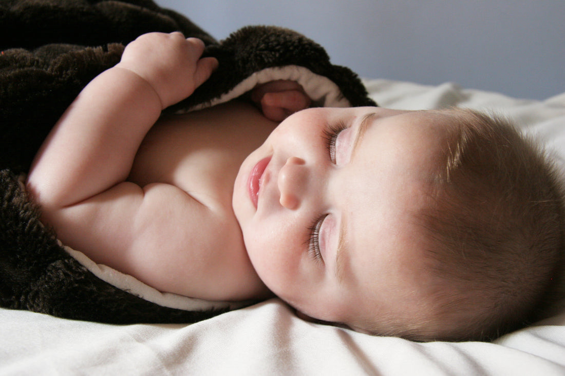 Sleeping baby wrapped in quilt | Nourish Baby