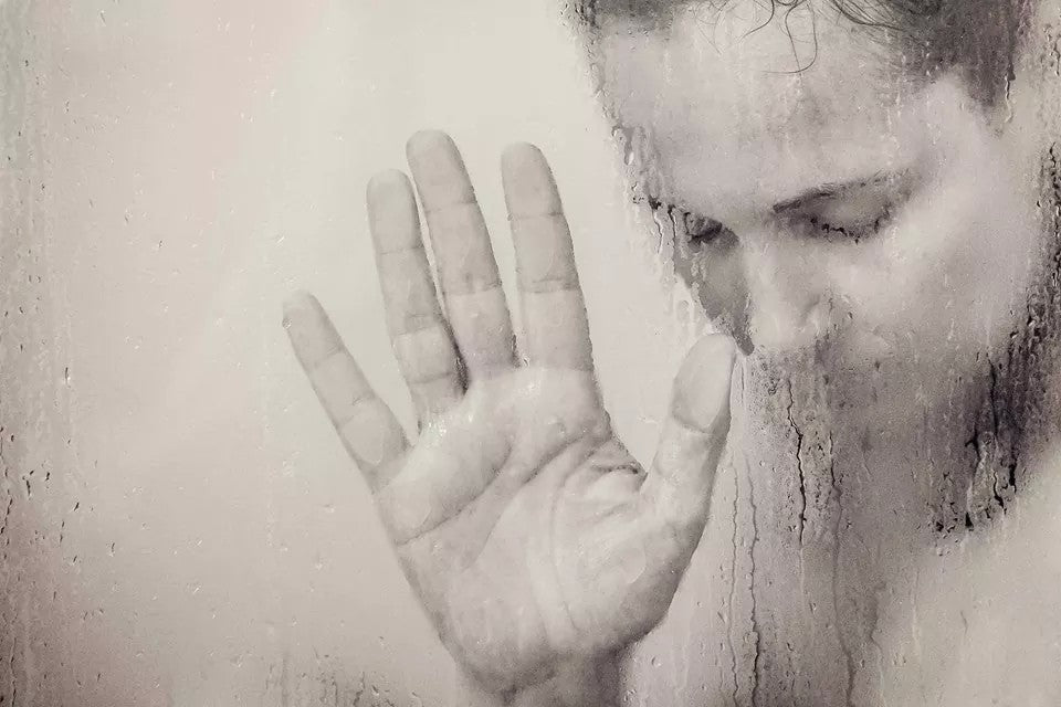 Woman in shower with her hand on the glass shower screen | Nourish Baby