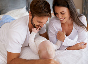Parents with baby on bed | Nourish Baby