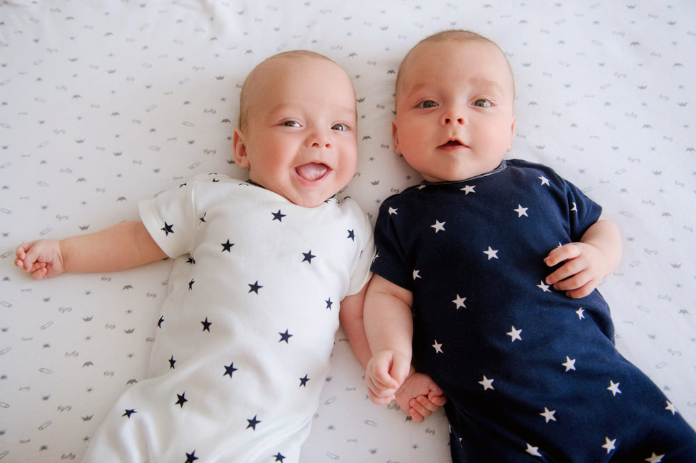 Twin babies laying next to each other | Nourish Baby