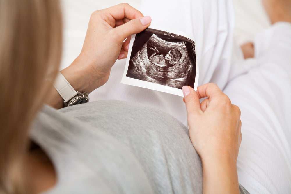 Woman looking at a baby scan photo | Nourish Baby