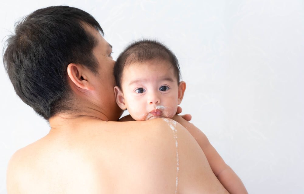 baby spitting up on dad's shoulder
