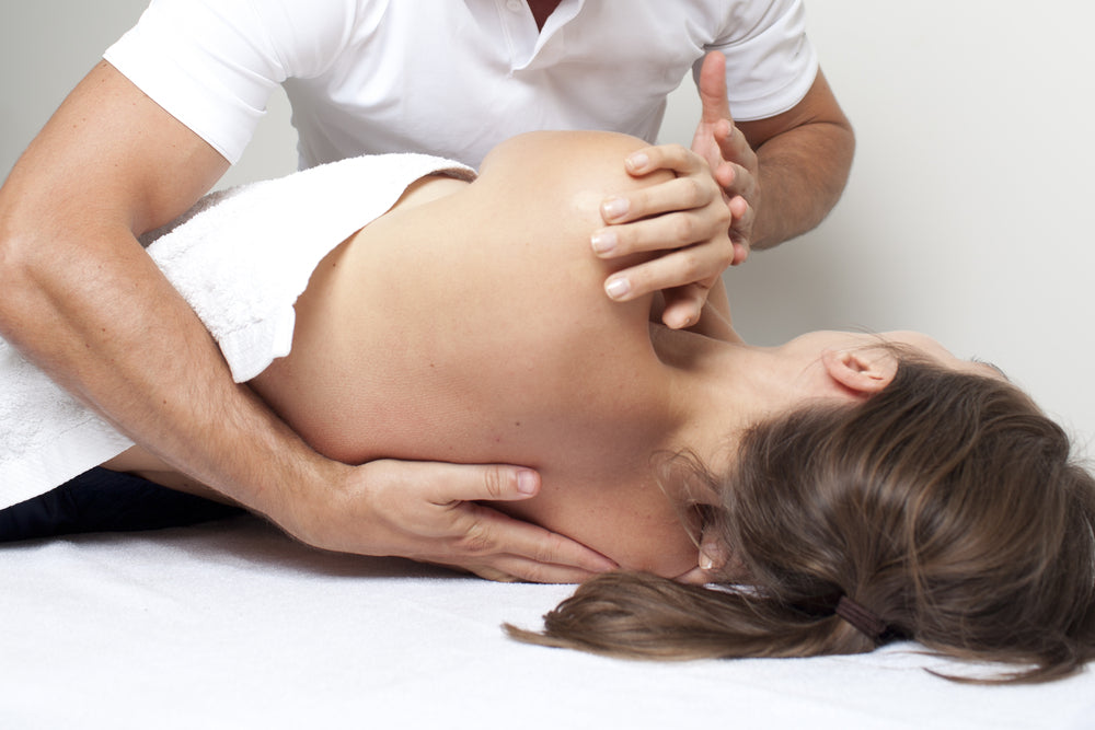 Osteopath treating woman laying on bed | Nourish Baby