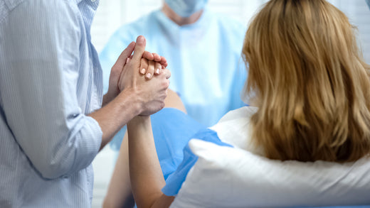 Woman in labour holding man's hand | Nourish Baby