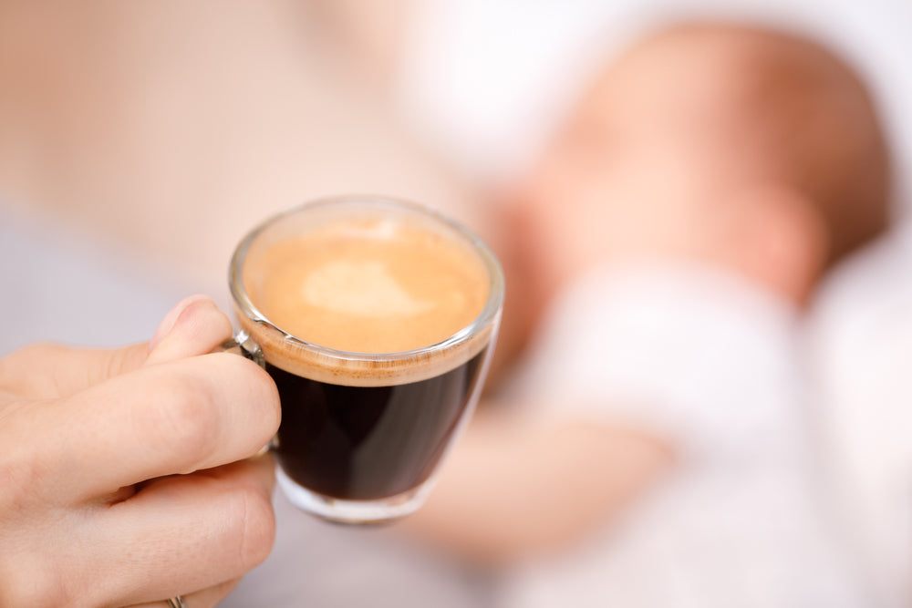 Cup of coffee with baby in background | Nourish Baby