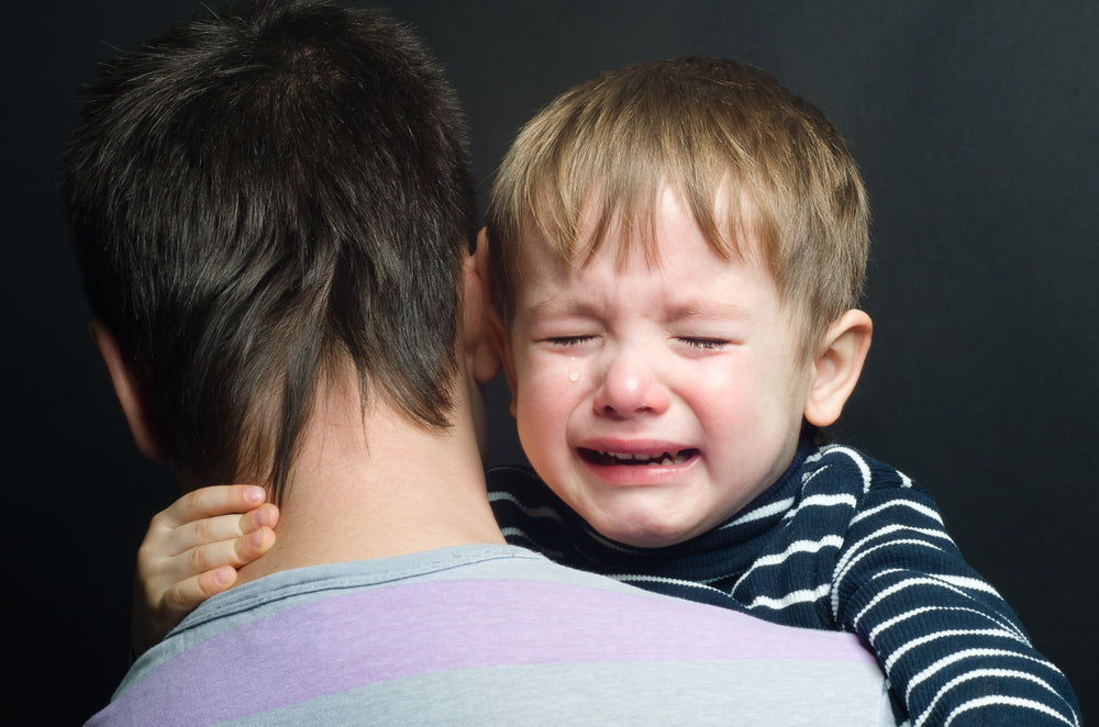 Crying boy being held by father | Nourish Baby