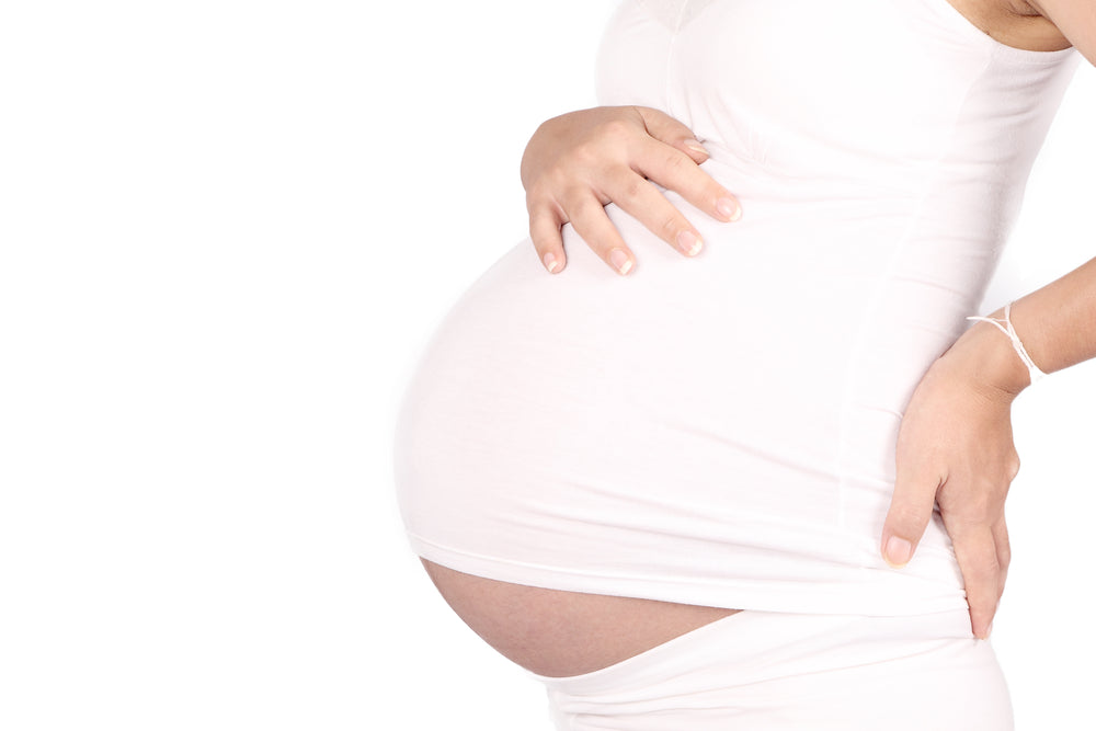 Woman holding back and baby bump | Nourish Baby