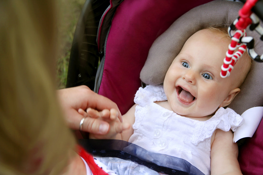 Laughing baby in stroller with mother | Nourish Baby