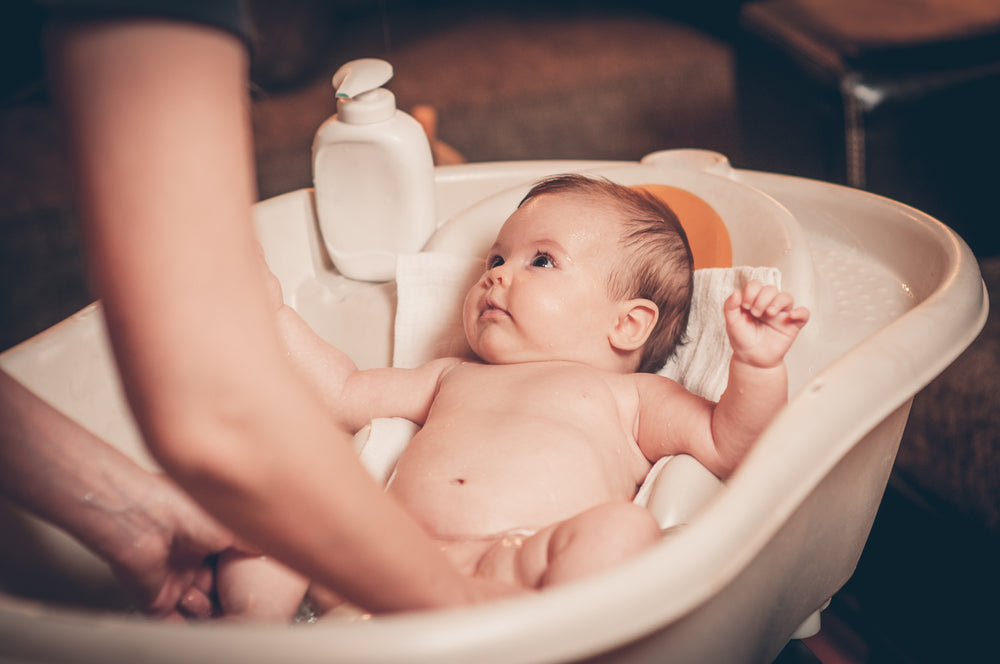 Baby being bathed by mother | Nourish Baby