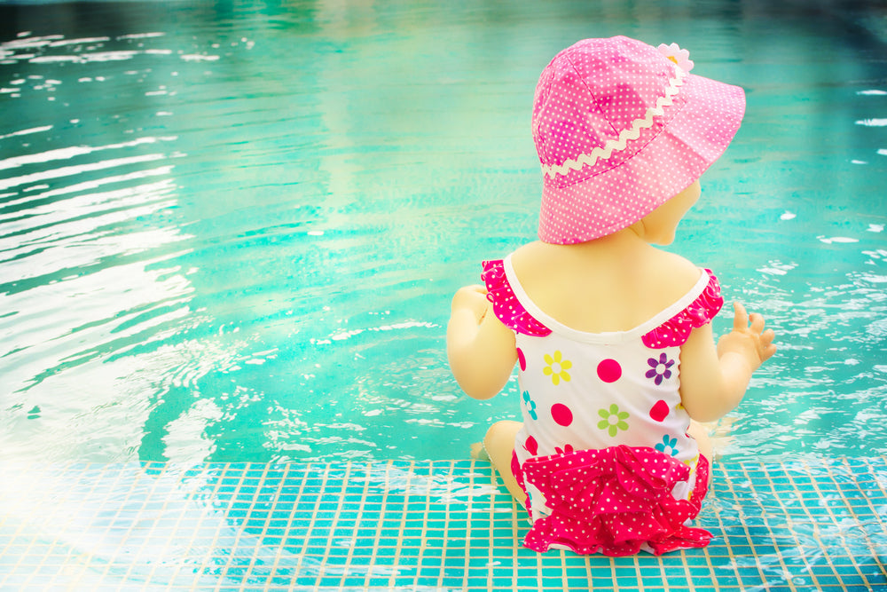 Toddler sitting in shallow end of pool | Nourish Baby