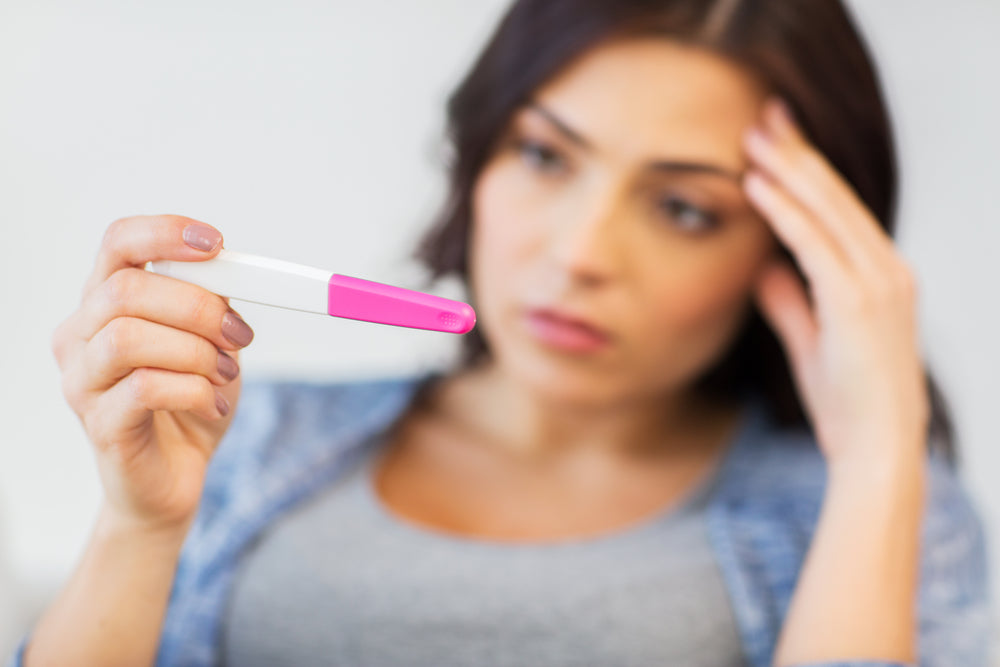 Woman looking at a pregnancy test | Nourish Baby