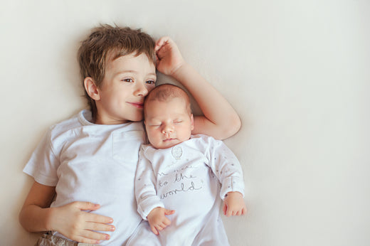 Boy laying with baby sibling | Nourish Baby