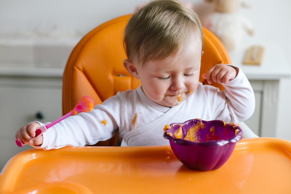 Baby feeding self in high chair | Nourish Baby