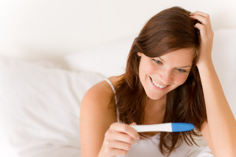 Woman looking at pregnancy test | Nourish Baby